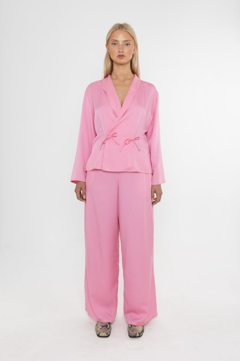 Woman wearing a Deidei pink trouser suit on a white background