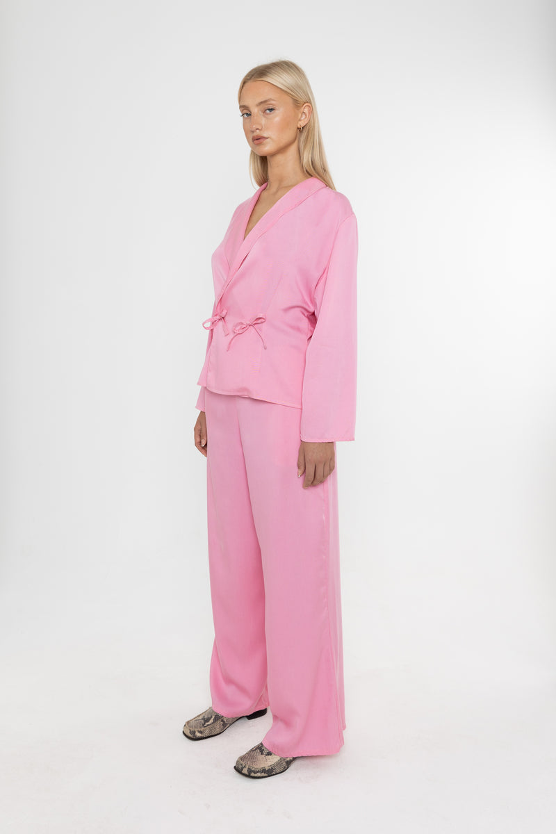 Woman wearing a Deidei pink tencel suit holding on a white background