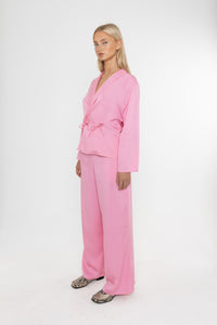 Woman wearing a Deidei pink tencel suit holding on a white background