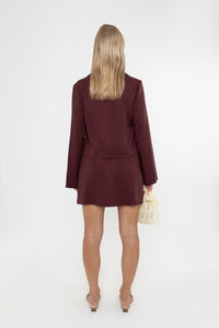 Woman wearing a Deidei burgundy brown Ada and Noor Skirt Suit with a white background