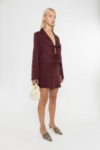 Woman wearing a Deidei burgundy brown Ada and Noor Skirt Suit with a white background