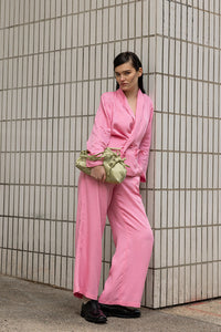 Person wearing a bright pink outfit standing against a tiled wall.