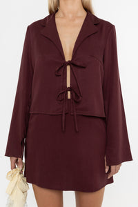 Woman wearing a burgundy brown jacket and mini skirt on a white background