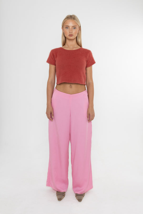 Woman wearing a red angora cropped top and Deidei Ella pink tencel wide-leg trousers on a white background