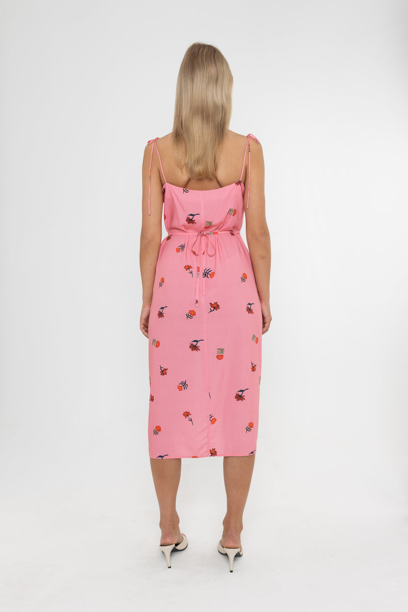 Woman wearing a Deidei Emmeline midi slip dress with pink floral rose print holding a blue vintage bag on a white background