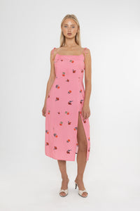Woman wearing a Deidei Emmeline midi slip dress with pink floral rose print holding a blue vintage bag on a white background