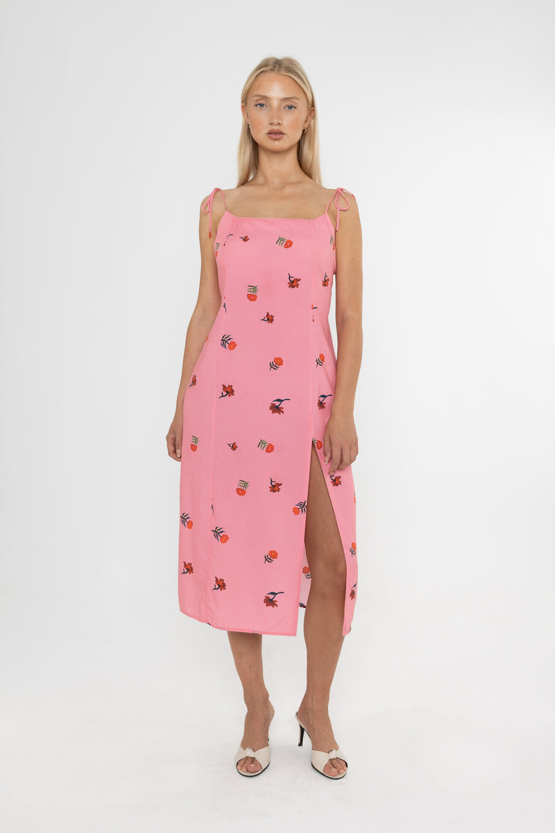 Woman wearing a Deidei Emmeline midi slip dress with pink floral rose print holding a blue vintage bag on a white background