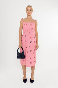 Woman wearing a Deidei Emmeline midi slip dress with pink floral rose print holding a blue vintage bag
