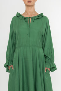 Woman wearing a green Deidei Florence dress with long sleeves and a ruffle collar on a white background