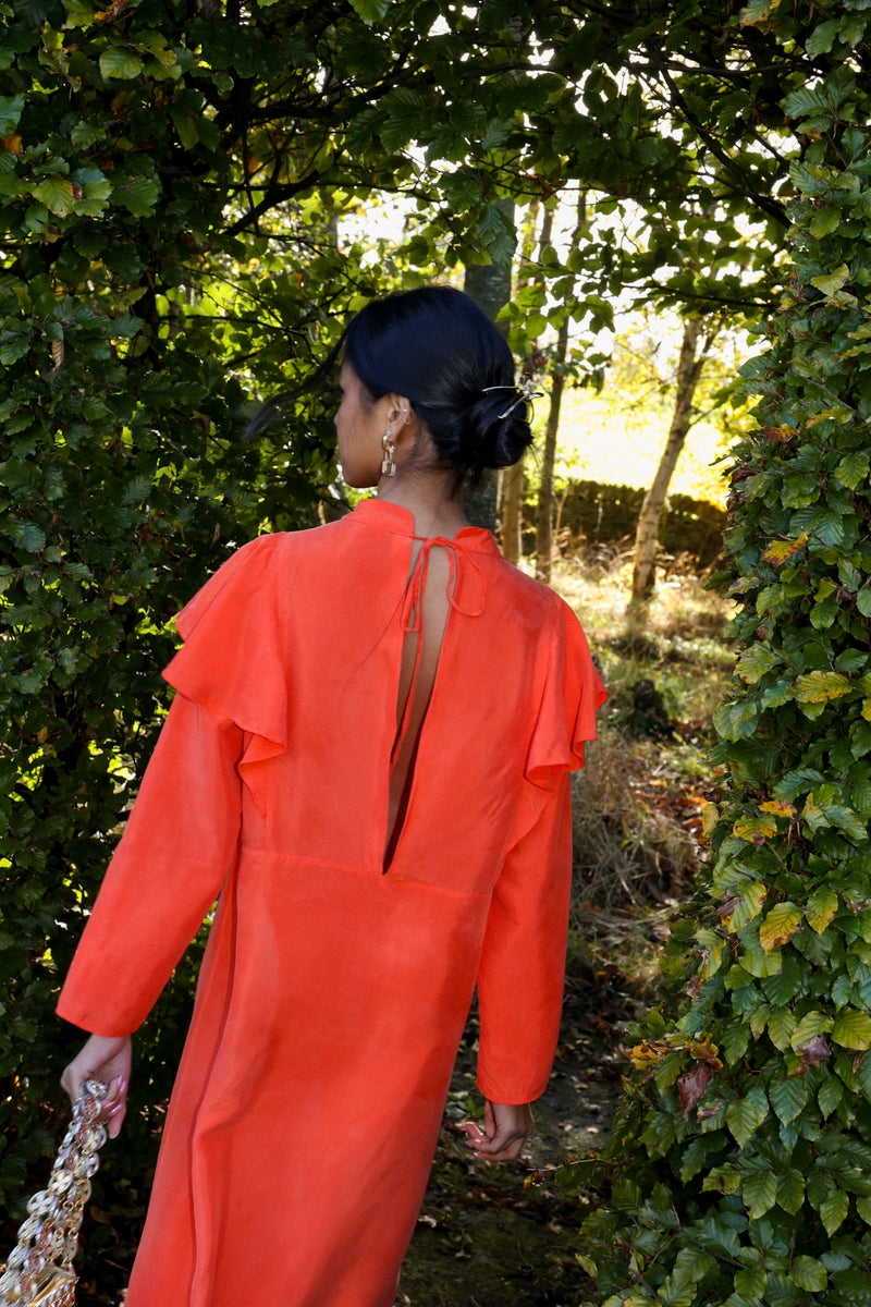model wears a sustainable deidei midi dress with long sleeves in orange cupro